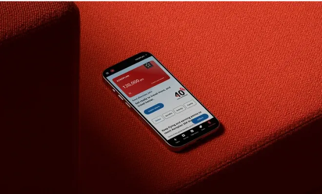 Smartphone displaying the Aeroplan app with loyalty points, resting on a red fabric surface.