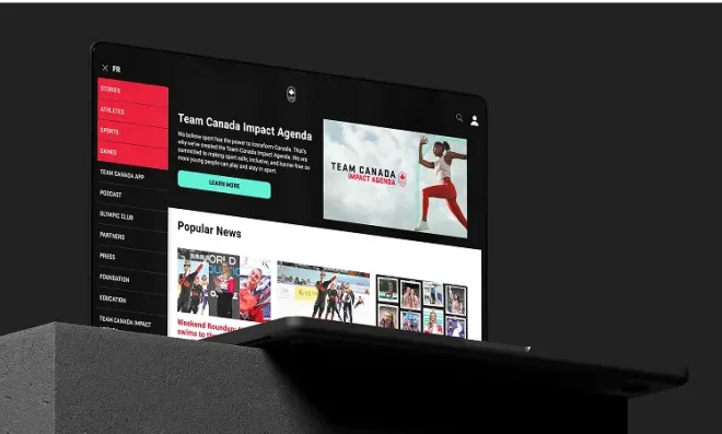 Laptop screen showing the Canadian Olympic Committee website, featuring athlete stories, sports menu, and the Team Canada Impact Agenda banner.