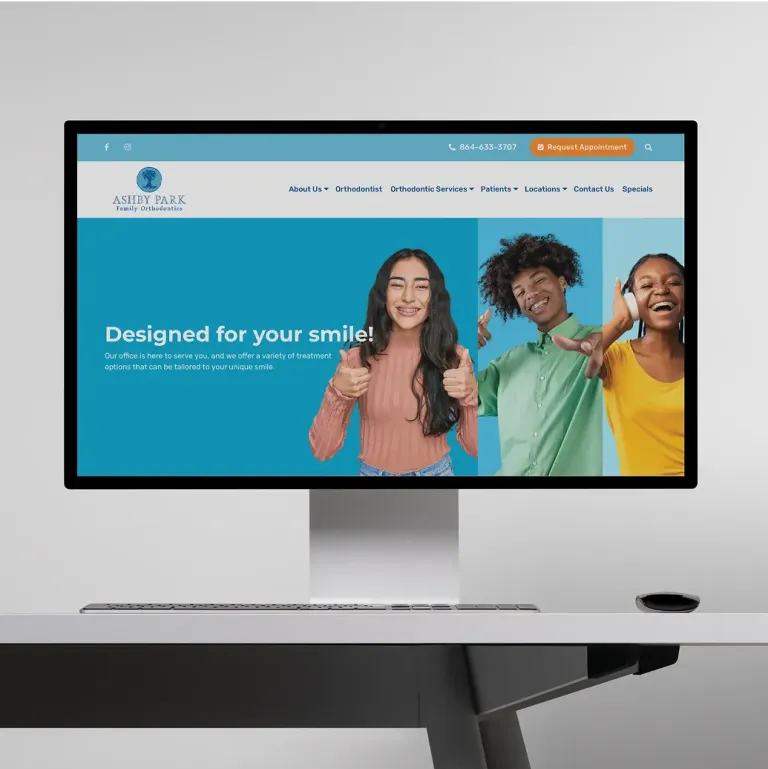 A computer screen displays a dental clinic website featuring smiling teens giving thumbs up.