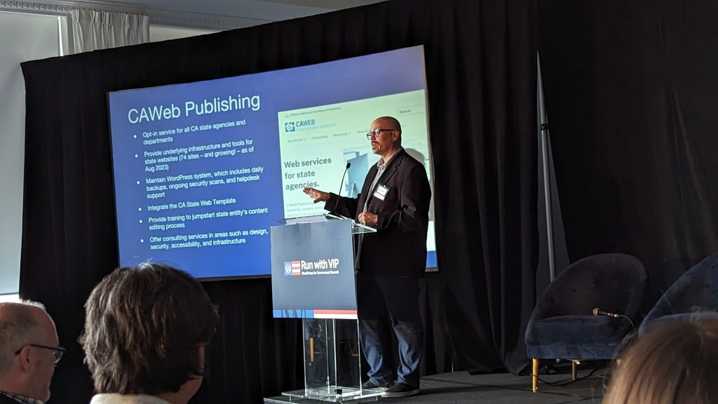 A person giving talk in front of an audience with "CAWeb Publishing" slide in the background