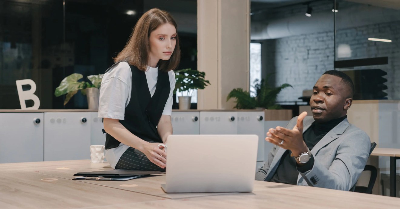 A person sitting at a table who is showing a self hosted Wordpress provider on a laptop to another person who is sitting on the table