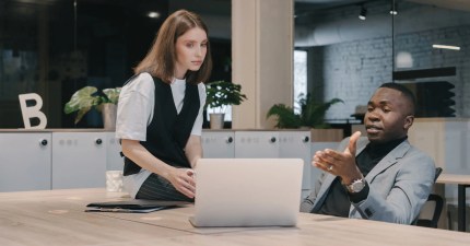 A person sitting at a table who is showing a self hosted Wordpress provider on a laptop to another person who is sitting on the table