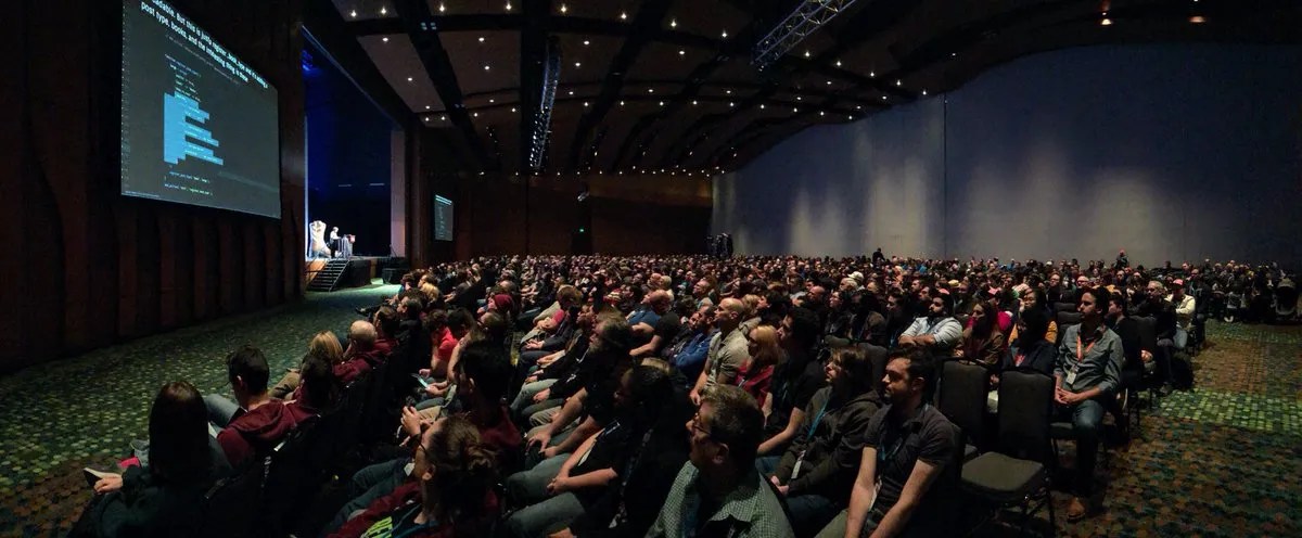 Audience viewing a live coding presentation with content workflow demo on a digital solution screen.