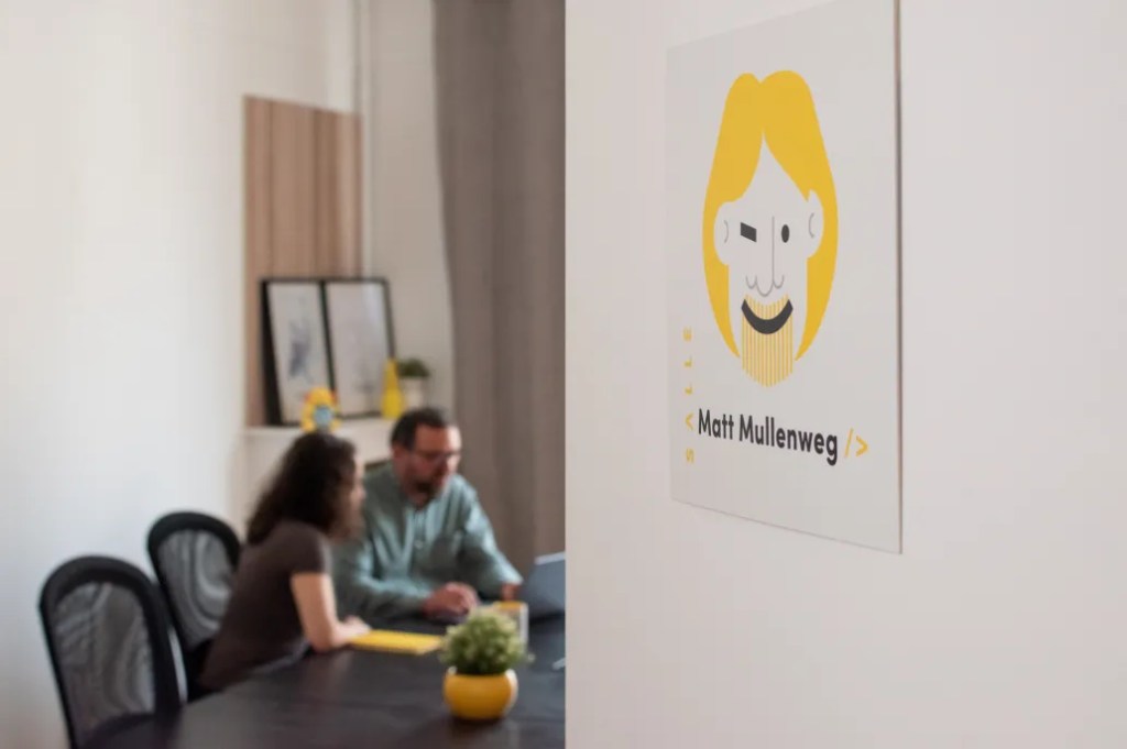 Two people collaborate at a table, discussing digital solution strategy and editorial workflow.