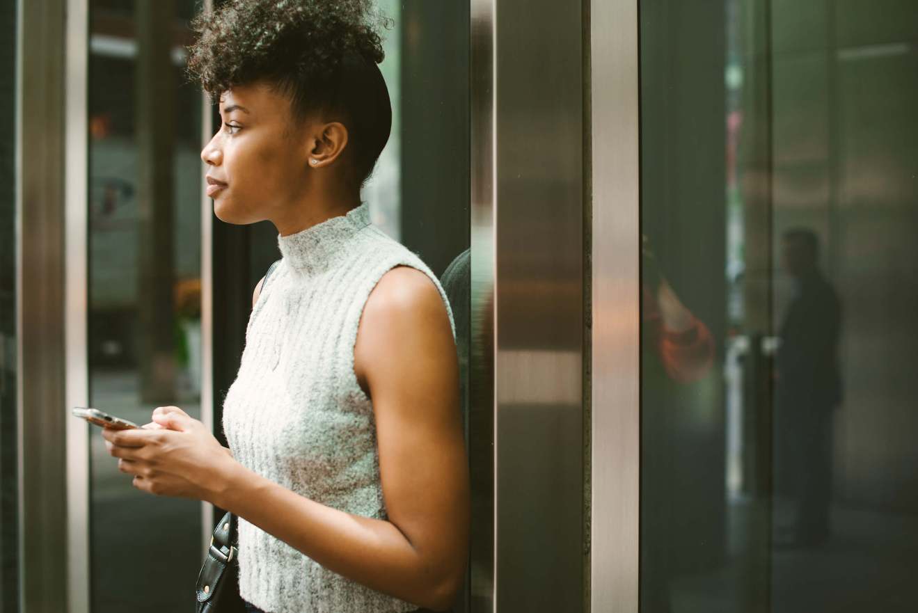 A person looking up from using a phone while in an elevator.