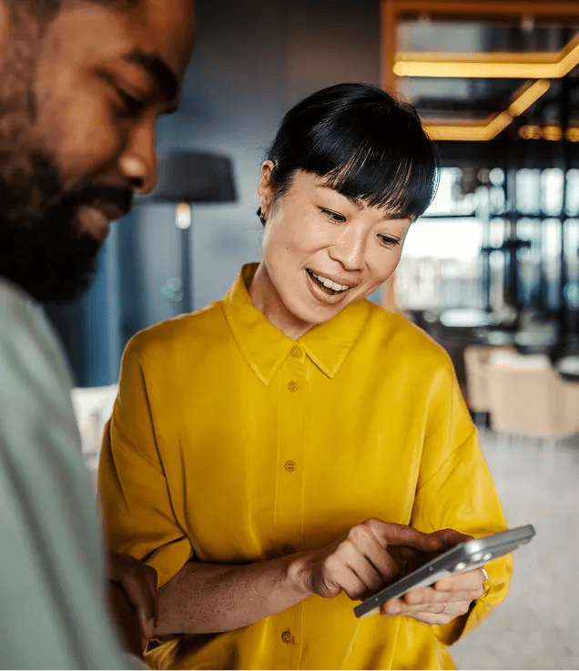 Person showing a smartphone screen to a colleague during a conversation.