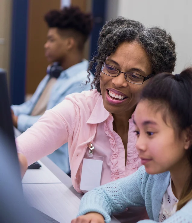 Close-up of a teacher and student collaborating at a computer.