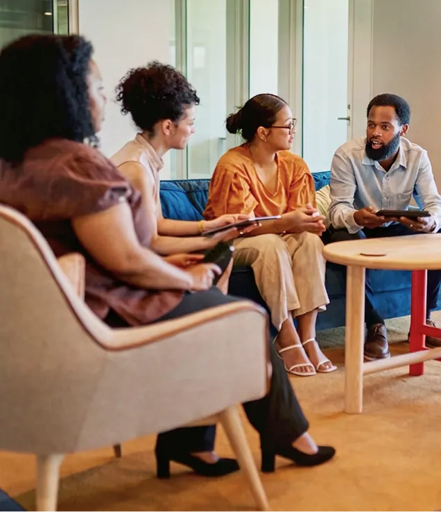 Colleagues engaged in a collaborative conversation in an office lounge.