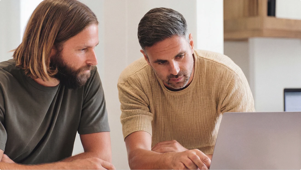 Two people reviewing content together on a laptop.
