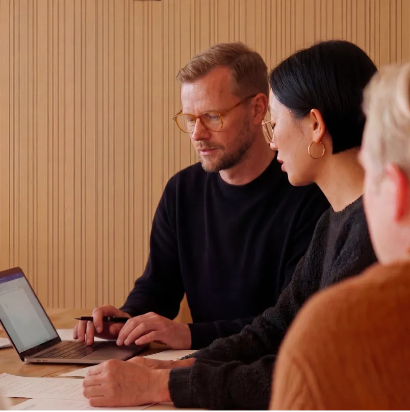 Three colleagues reviewing enterprise integration workflows together on a laptop during a planning session for technology partner implementations.